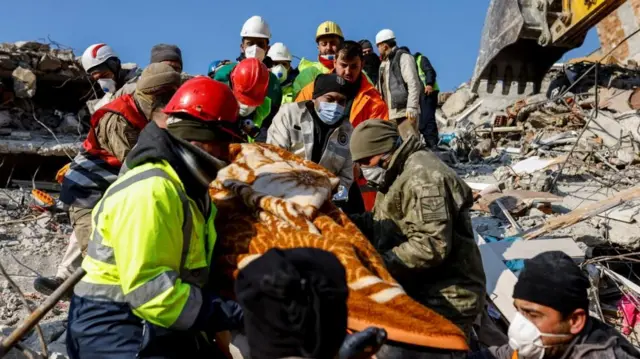 Rescuers carry a woman from a building demolished by the earthquake