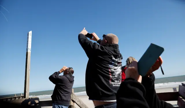 People photograph the suspected Chinese spy balloon as it floats off the coast in Surfside Beach, South Carolina