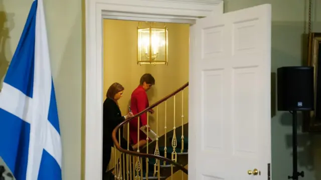 Nicola Sturgeon walks up a staircase in Bute House after concluding a press conference