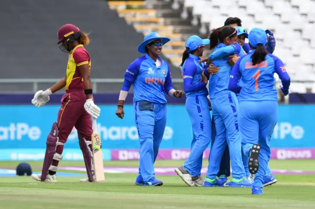 West Indies' Hayley Matthews (L) walks back to the pavilion after her dismissal as the India players celebrate during the Group B T20 women's World Cup cricket match between West Indies and India at Newlands Stadium in Cape Town