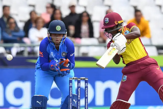 West Indies' Stafanie Taylor (R) plays a shot as India's wicketkeeper Richa Ghosh (R) looks on during the Group B T20 women's World Cup cricket match between West Indies and India at Newlands Stadium in Cape Town