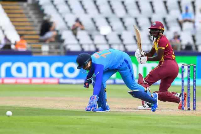 West Indies' Stafanie Taylor watches the ball after playing a shot as India's wicketkeeper Richa Ghosh (L) fields during the Group B T20 women's World Cup cricket match between West Indies and India at Newlands Stadium in Cape Town