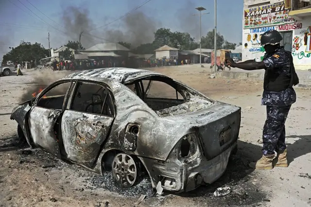 An African Union Mission in Somalia (AMISOM) soldier records details at the wreckage of a car bomb in the Wardhigley District south of Mogadishu