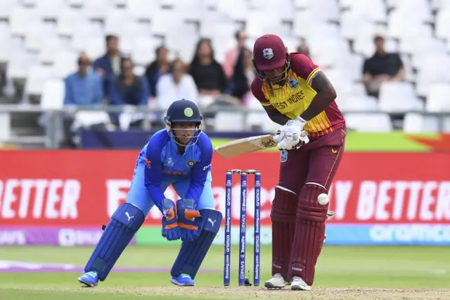 West Indies' Stafanie Taylor (R) plays a shot as India's wicketkeeper Richa Ghosh (L) looks on during the Group B T20 women's World Cup cricket match between West Indies and India at Newlands Stadium in Cape Town