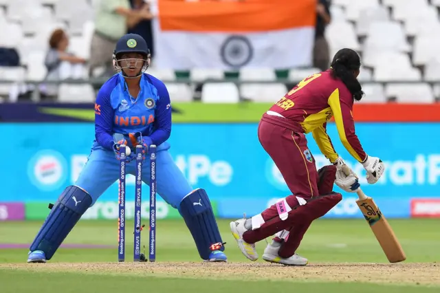 West Indies' Afy Fletcher (R) reacts after being bowled by India's Deepti Sharma (not seen) as India's wicketkeeper Richa Ghosh (L) reacts during the Group B T20 women's World Cup cricket match between West Indies and India at Newlands Stadium in Cape Town