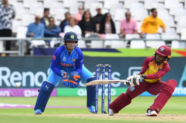 West Indies' Shemaine Campbelle (R) watches the ball after playing a shot as India's wicketkeeper Richa Ghosh (L) looks on during the Group B T20 women's World Cup cricket match between West Indies and India at Newlands Stadium in Cape Town