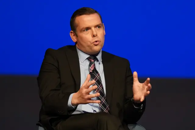 Scottish Tory leader Douglas Ross sits on stage at an event