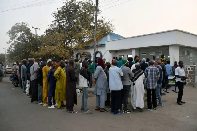 People queue early in the day to withdraw money from cash dispensers that is crippled by cash shortages at a bank in Kano, northwest Nigeria, on February 8, 2023