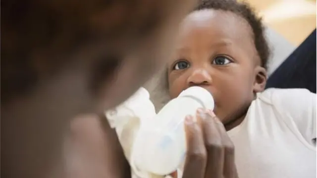 A baby drinking milk from a bottle.