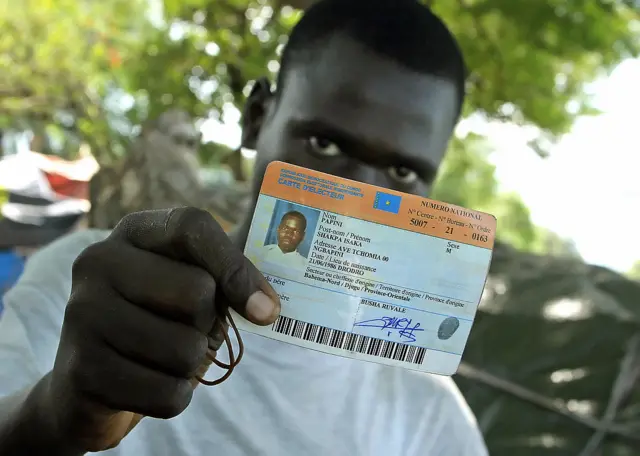 A man shows his voter registration card in DR Congo