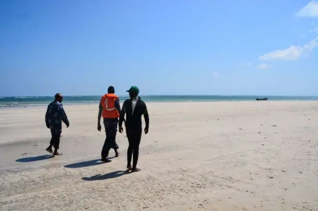 Police officers walk along a beach to search bodies of victims after the capsizing of two boats earlier this week off Djibouti's northeastern Obock region, on January 31, 2019