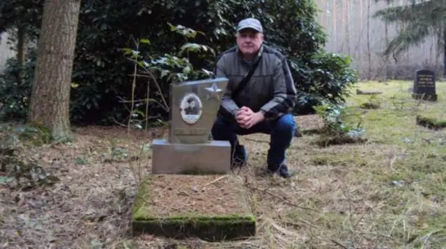 David Smith seen crouching next to a grave