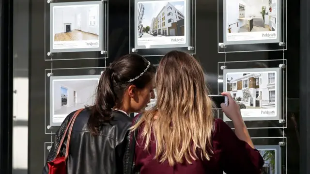 Women look at properties in an estate agent's window