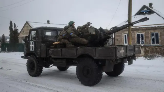 Ukrainian servicemen ride on a military vehicle in the front line city of Vuhledar