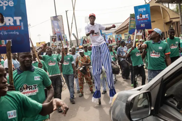 A man on stilts and other campaigners attend a rally in Lagos ahead of presidential elections in Nigeria