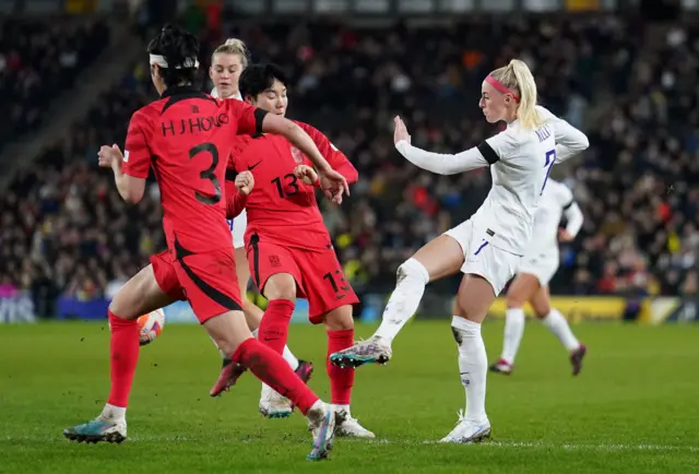 Chloe Kelly shoots for England under pressure from two Belgium defenders