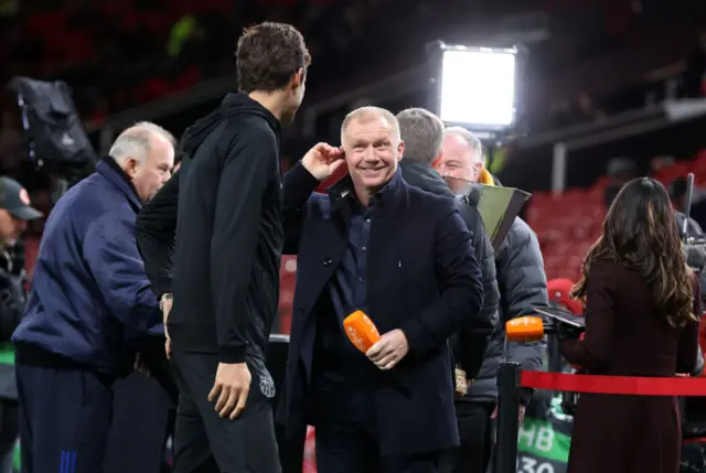 Pundit Scholes smiles while pitchside.