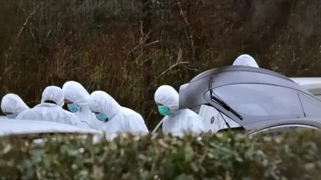 Forensic officers search cars at scene of a shooting in Omagh