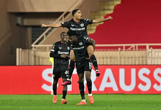 Amine Adli of Bayer 04 Leverkusen celebrates with teammate Edmond Tapsoba and Jeremie Frimpong