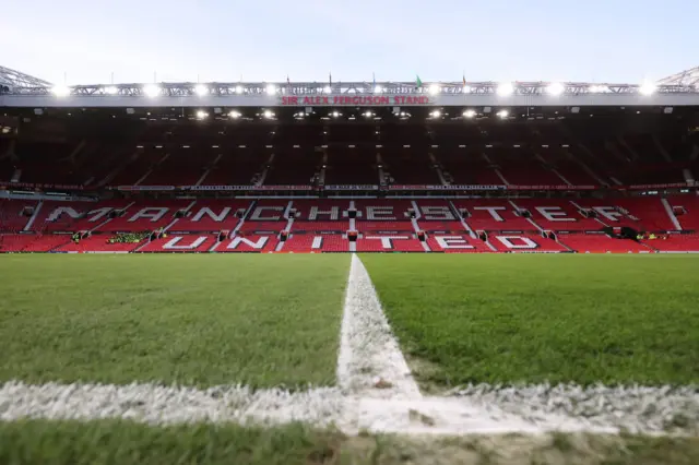 Old Trafford lit up by its floodlights.