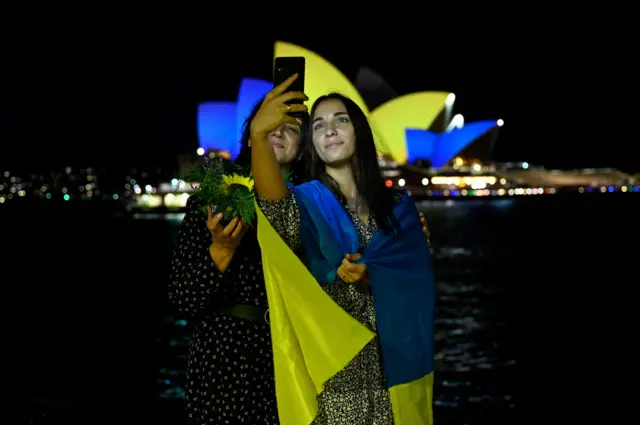 Two women taking a photo in front of Sydney Opera House