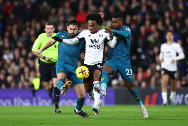 Willian of Fulham battles for possession with Ruben Neves and Nelson Semedo of Wolves