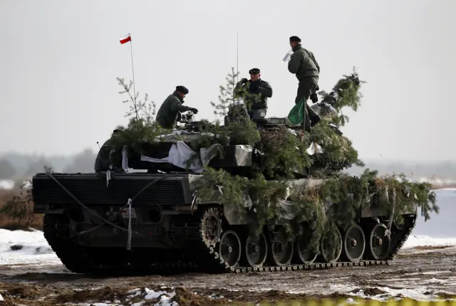 Polish army soldiers atop their Leopard 2A4 tank after a live-firing exercise