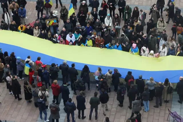 People gathered around a large Ukrainian flag