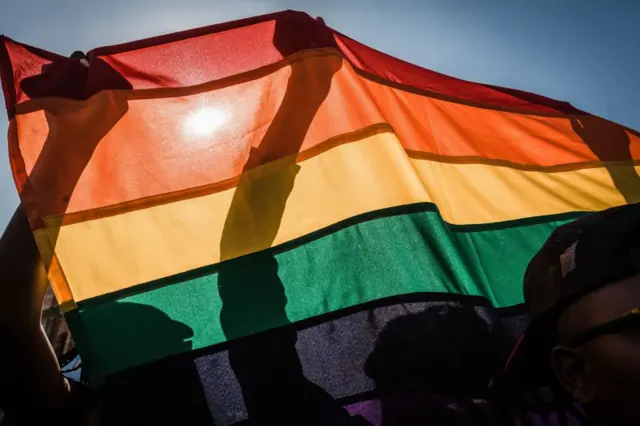 People holding up an LGBTQ rainbow flag.