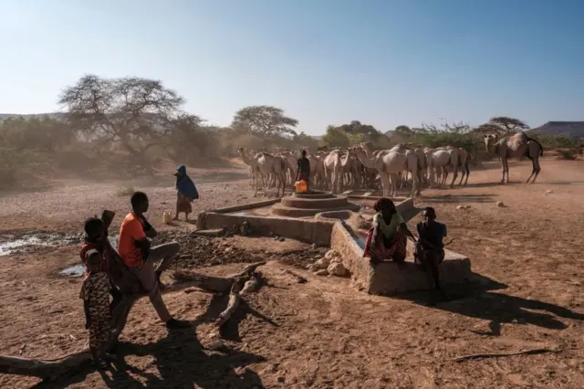 People stand next to a water well at the village of El Gel, 8 kilometres from the town of K'elafo, Ethiopia, on January 12, 2023.