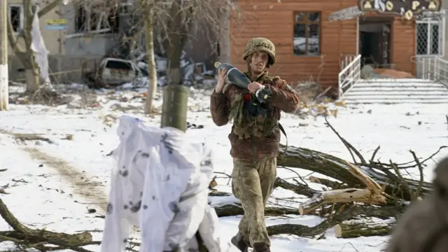 A soldier carrying a mortar shell in Vuhledar