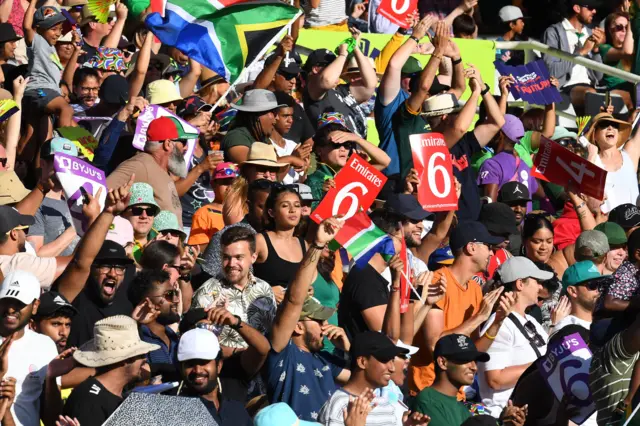 outh African supporters celebrate after South Africa's Laura Wolvaardt (not seen) hit a six during the final T20 women's World Cup cricket match between South Africa and Australia at Newlands Stadium in Cape Town