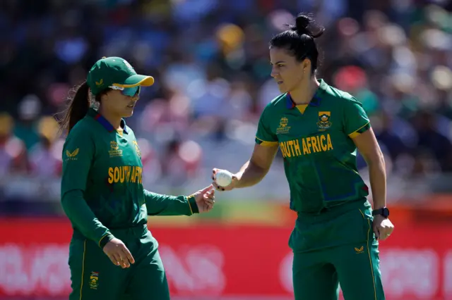 South Africa's Sune Luus (L) hands the ball to South Africa's Marizanne Kapp (R) during the final T20 women's World Cup cricket match between South Africa and Australia at Newlands Stadium in Cape Town