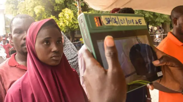 An electoral official uses an electronic device to check a voter's identity in Abuja, Saturday 25 February 2023