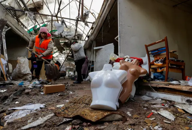 A woman sweeps away debris in Horlivka, Donetsk