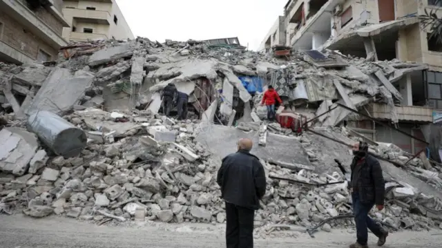 Rescuers work at the site of a collapsed building following an earthquake in Armanaz town, Idlib Governorate, Syria