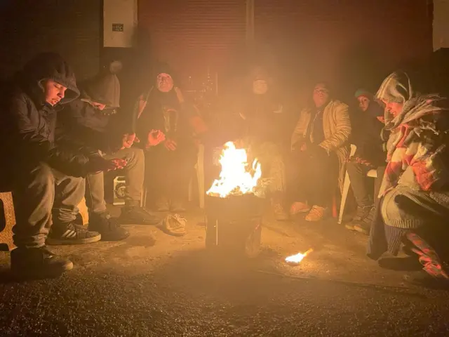 A group of people sit around a fire to keep warm after the earthquakes