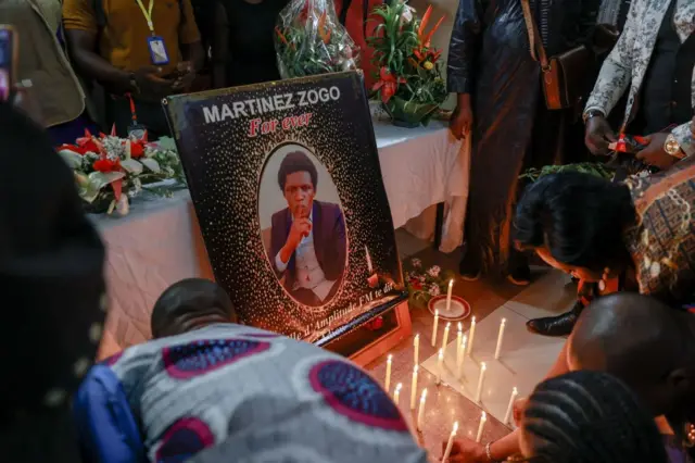 Colleagues light candles in Martinez Zogo's memory.