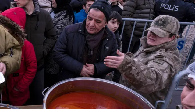 Police and security personnel guide people waiting for food in Diyarbakir