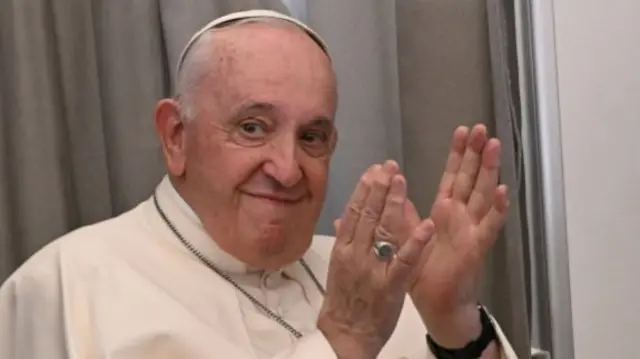 Pope Francis reacts as he addresses the media while aboard the plane from Juba to Rome