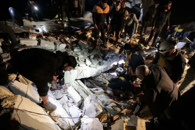 People look on as Syrian rescuers (White Helmets) retrieve an injured man from the rubble of a collapsed building follwoing an earthquake, in the border town of Azaz in the rebel-held north of the Aleppo province, early on February 6, 2023, - At least 42 have been reportedly killed in north Syria after a 7.8-magnitude earthquake that originated in Turkey and was felt across neighbouring countries. (Photo by Bakr ALKASEM / AFP) (Photo by BAKR ALKASEM/AFP via Getty Images)