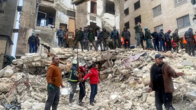 Rescuers search for survivors under the rubble of a collapsed building in Hama, Syria