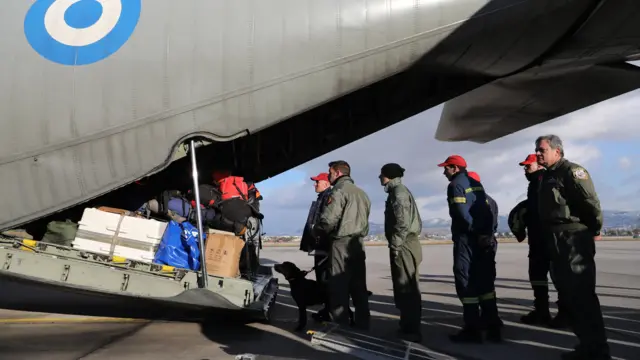 People and a dog about to board a military plane via a ramp