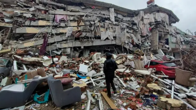 A man stands in front of collapsed buildings following an earthquake in Kahramanmaras, Turkey