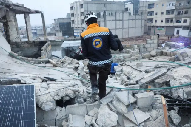 A rescue worker carries a child at the site of a damaged building, following an earthquake, in rebel-held Azaz, Syria