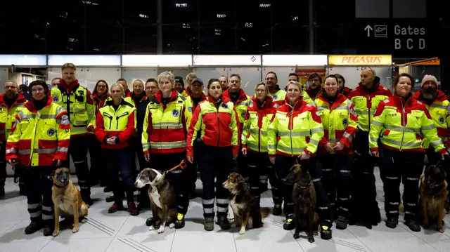 Men and women in reflective jackets stand with their rescue dogs