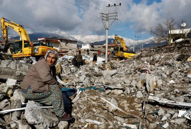 A woman sitting by ruined buildings in Gaziantep, Turkey