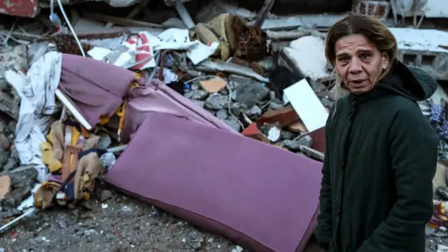 Woman stands amidst debris