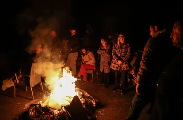 People warm themselves up around a fire in Hatay, Turkey