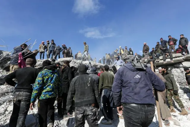 People searching for survivors in Jandaris, Syria